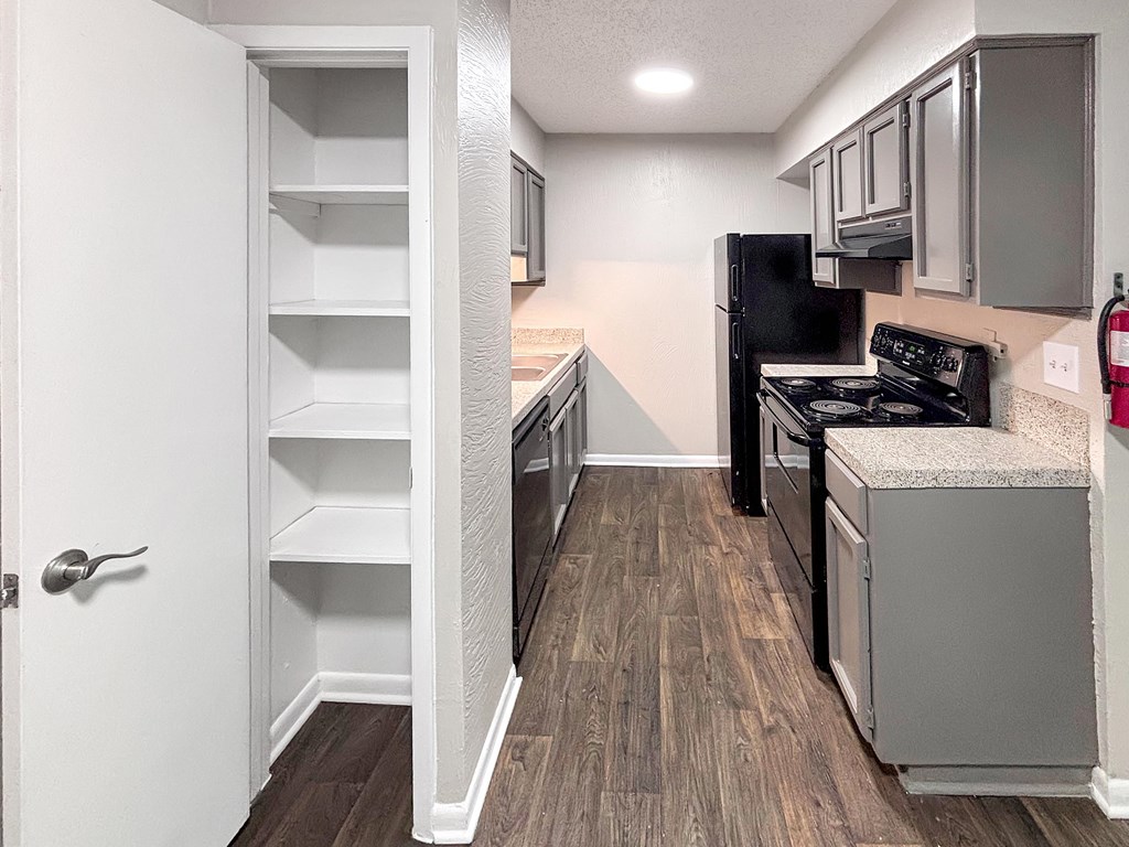 A kitchen with a black fridge and stove, and a white door.