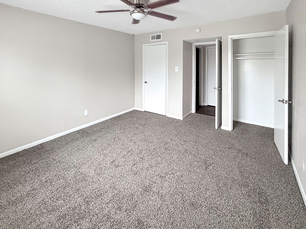 A room with a ceiling fan and carpeted floor.