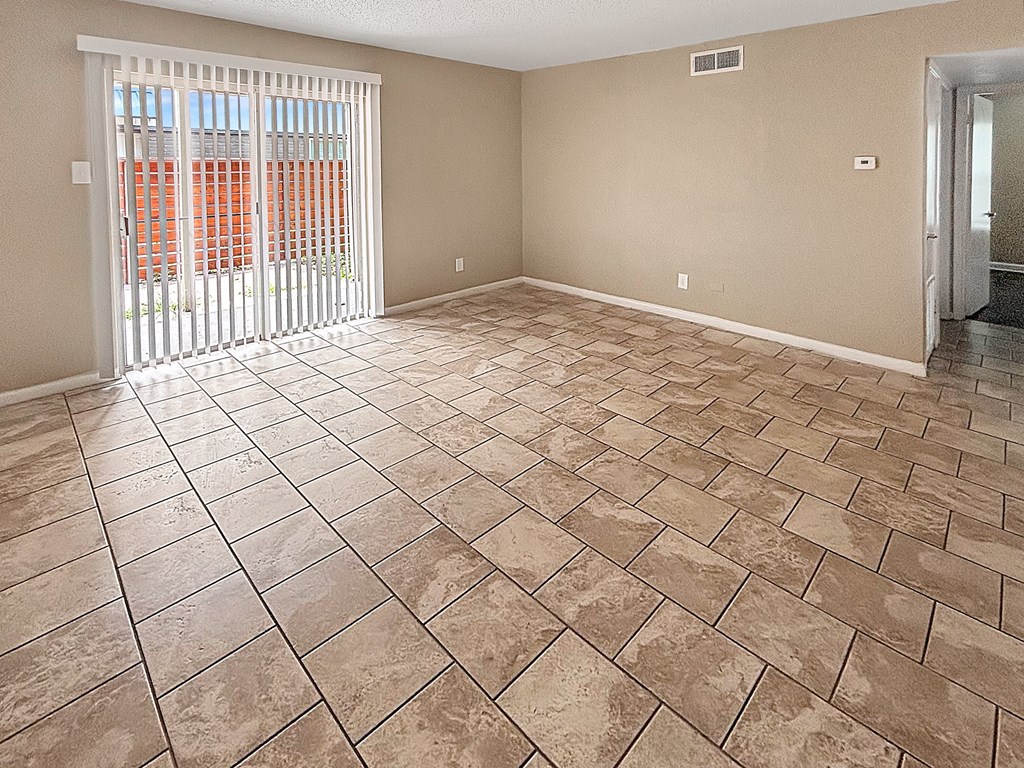 A room with tiled flooring and a sliding glass door.