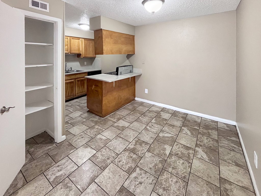 Kitchen with wood cabinetry and tile floor at Christy Estates Apartments