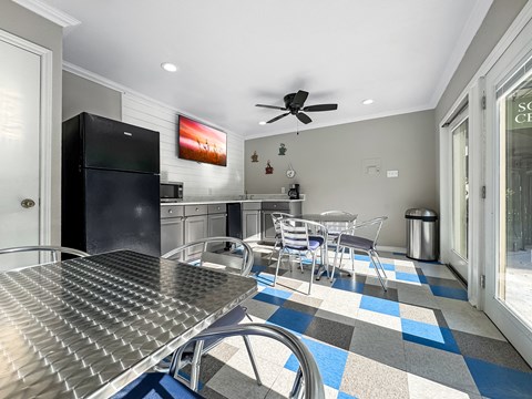 A kitchen with a black fridge and a dining table with chairs.
