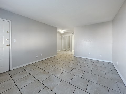 Large living room with neutral walls and tile floors at Los Cedros Apartments