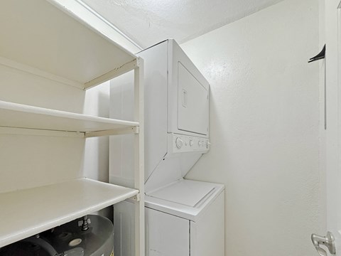 Stacked washer and dryer in laundry closet at Los Cedros Apartments