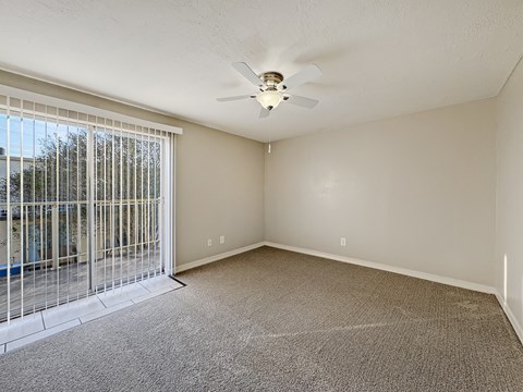 Bedroom with beige carpet, ceiling fan, and natural light at Los Cedros Apartments