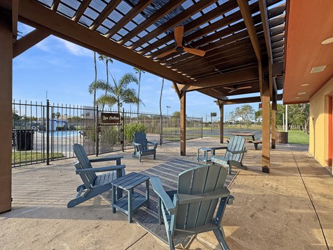 Covered pergola with seating near pool at Los Cedros Apartments