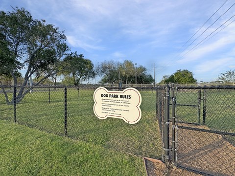Gated dog park with entry sign at Los Cedros Apartments
