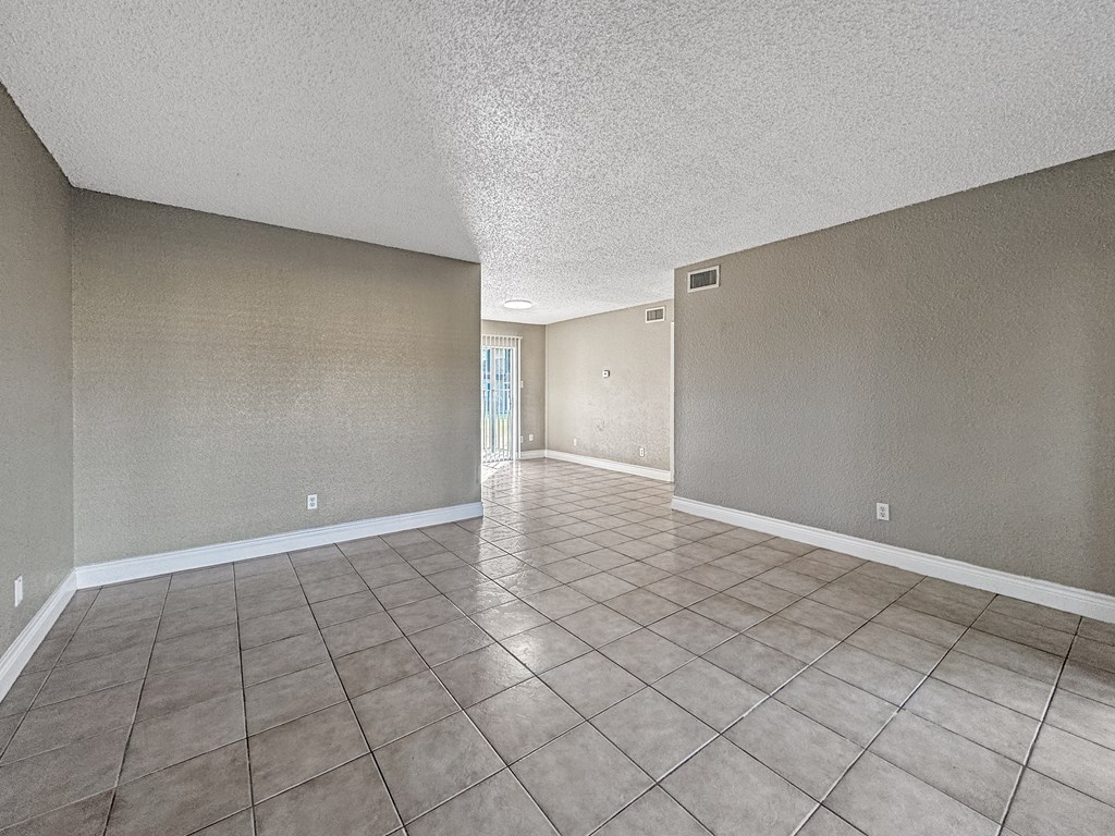 A spacious room with tile flooring and beige walls.