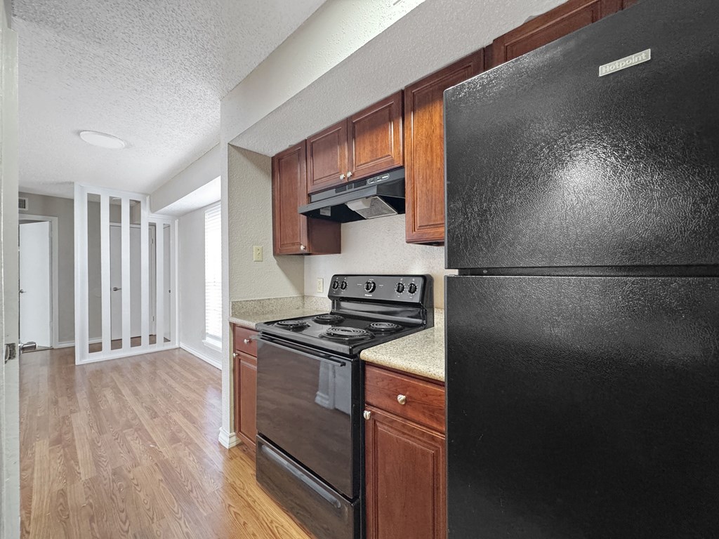Kitchen with dark wood cabinets and black appliances – Borders Apartments Brownsville TX