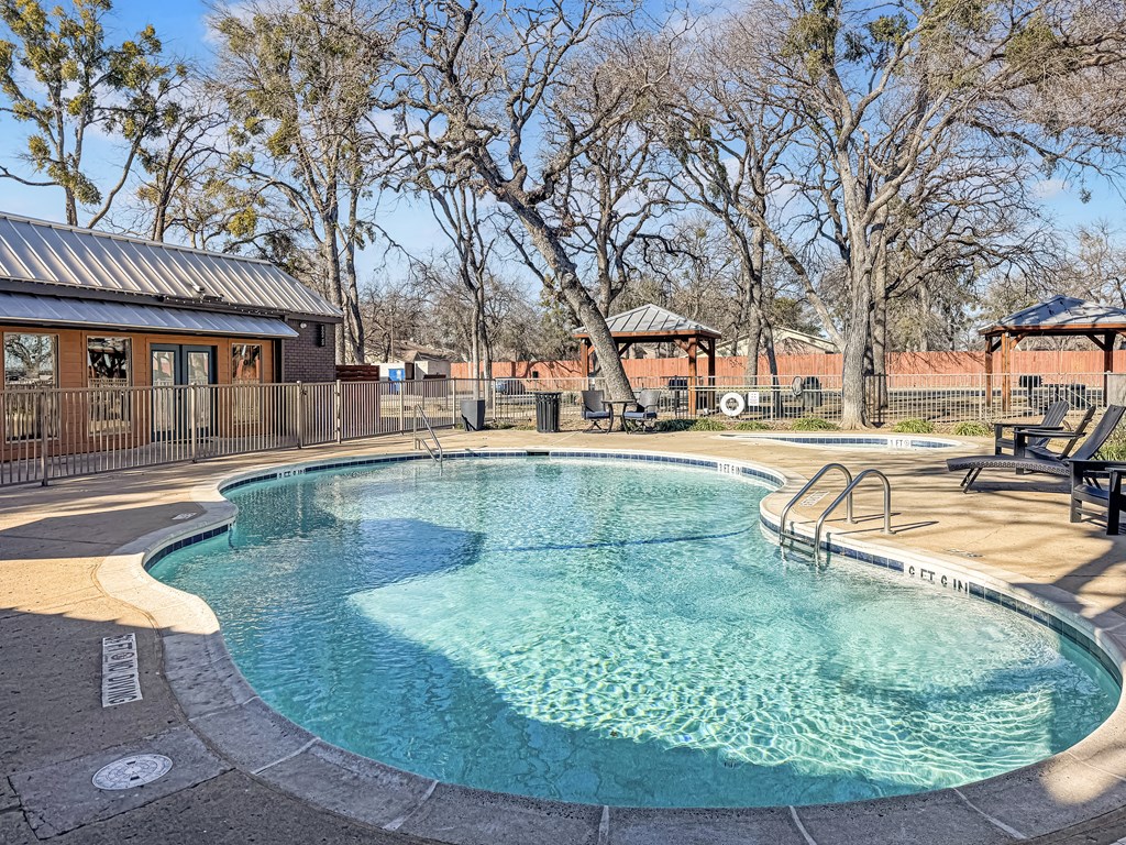 Swimming pool with lounge chairs and landscaping at Verano Oaks Apartments