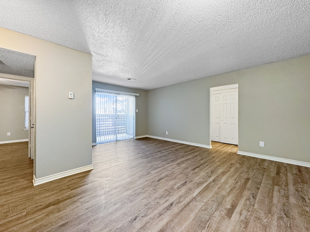 Spacious living room with neutral walls and wood-style flooring at Verano Oaks Apartments in Hurst, TX