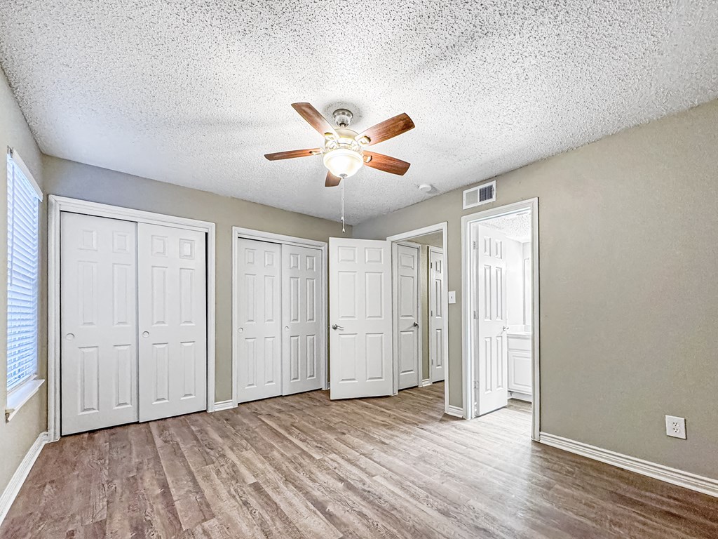 Bedroom with ceiling fan and large window at Verano Oaks Apartments