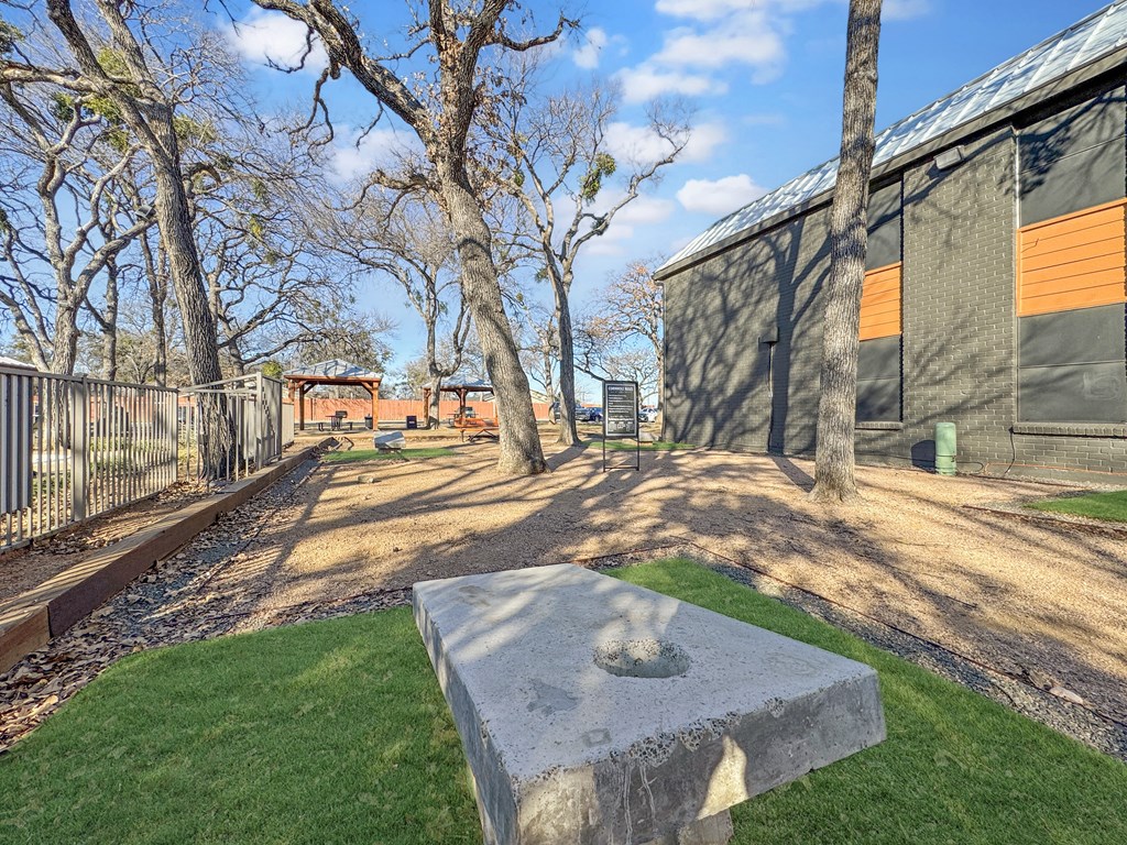 A concrete block with a hole in the middle is in the foreground of a grassy area.