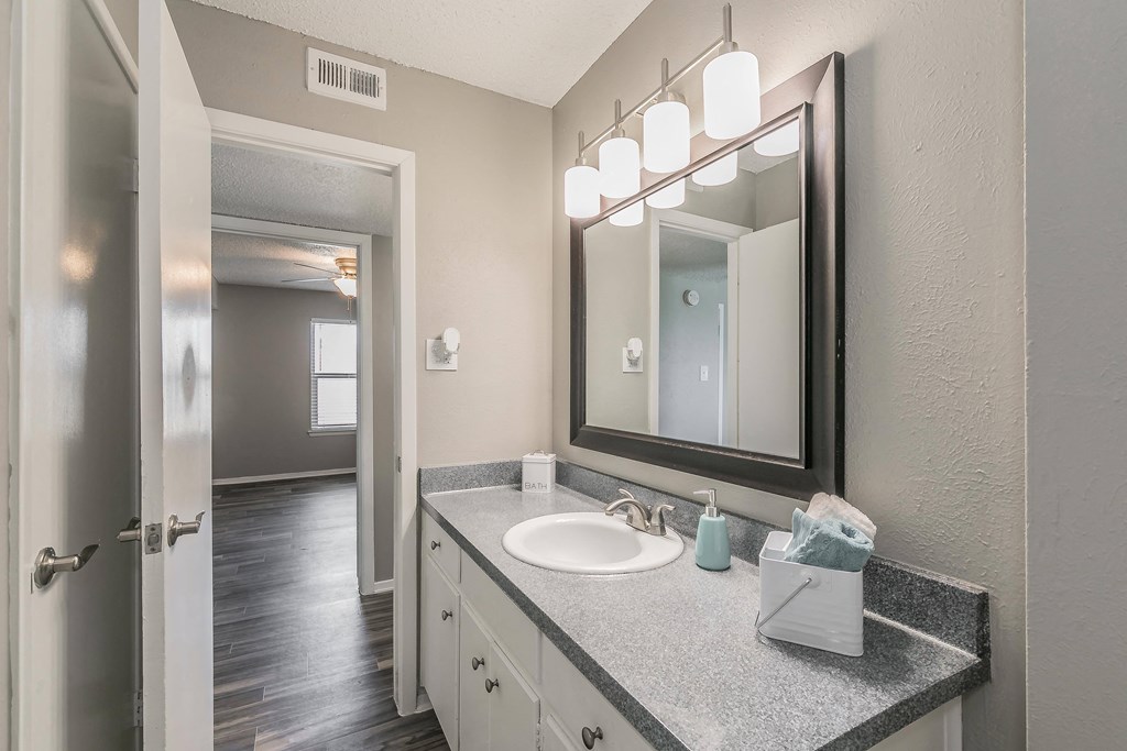 Bathroom with wide mirror, vanity lighting, and updated fixtures