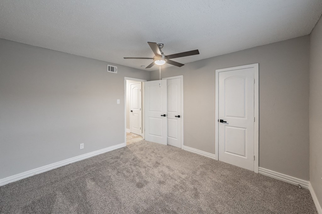Bedroom with carpet flooring and ceiling fan at Riata Park Apartments
