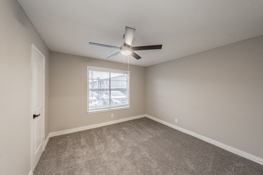 Bedroom with carpet flooring and ceiling fan at Riata Park Apartments