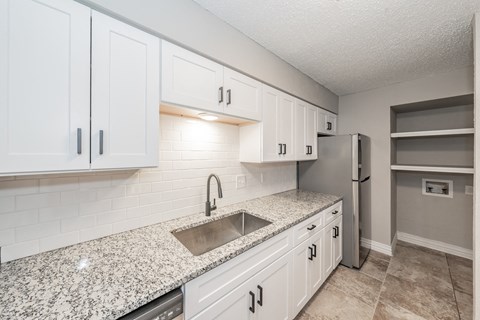 a kitchen with white cabinets and a sink and a refrigerator