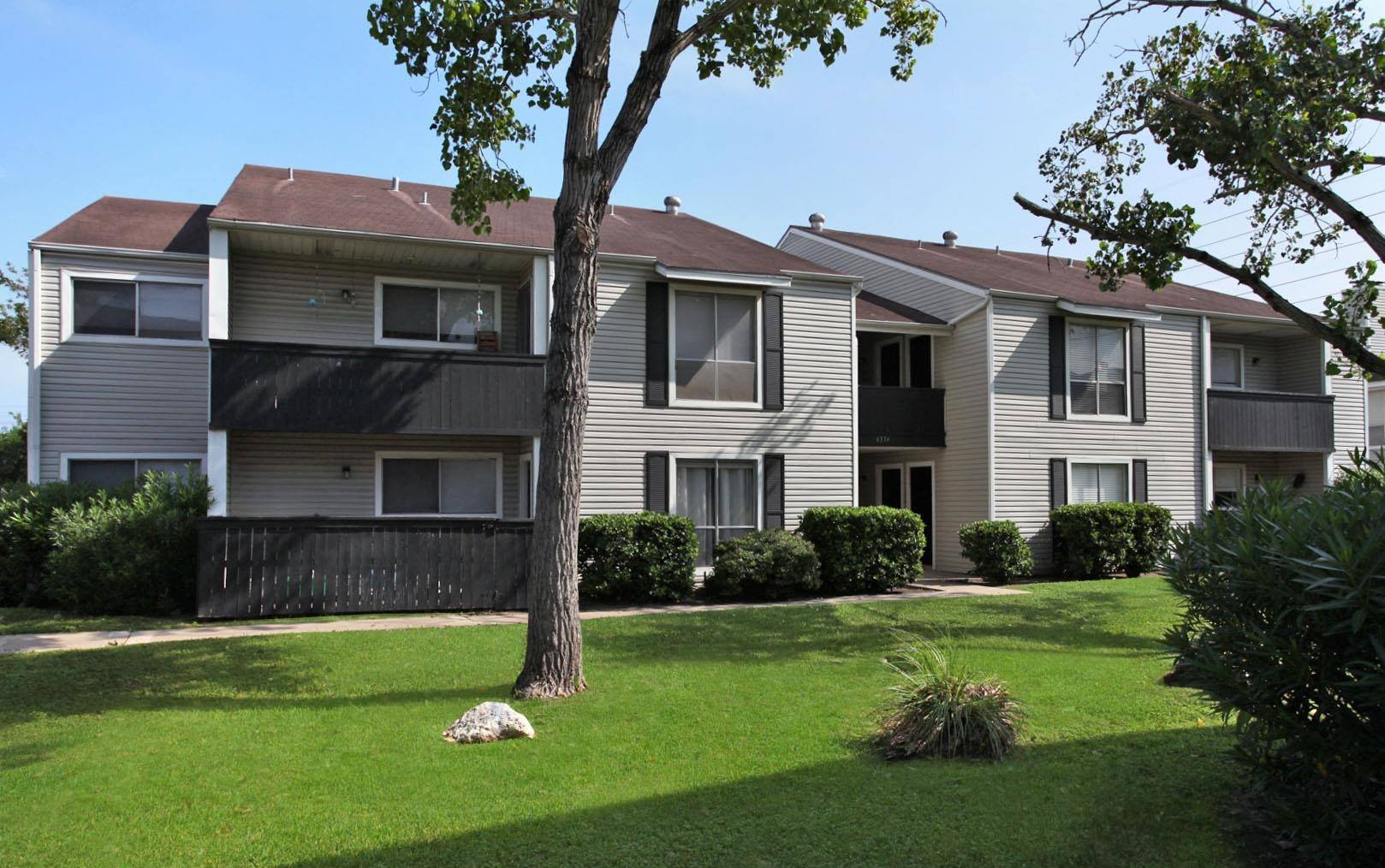 an apartment building with a lawn and a tree