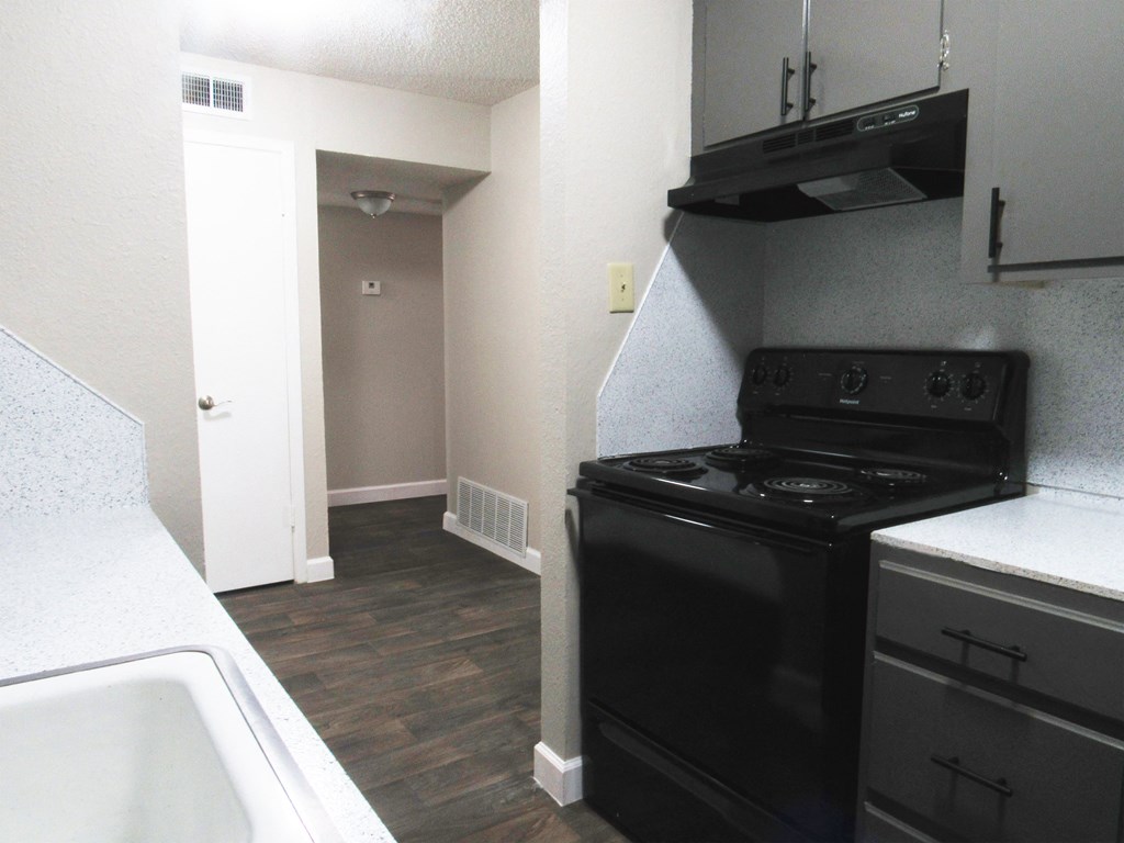 a kitchen with black appliances and a black stove and white counter tops