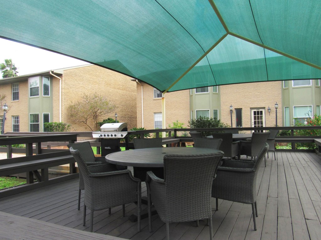 a patio with tables and chairs and a grill