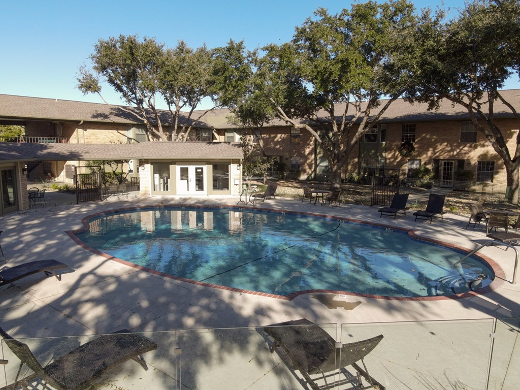 a large pool with chairs around it in front of a house