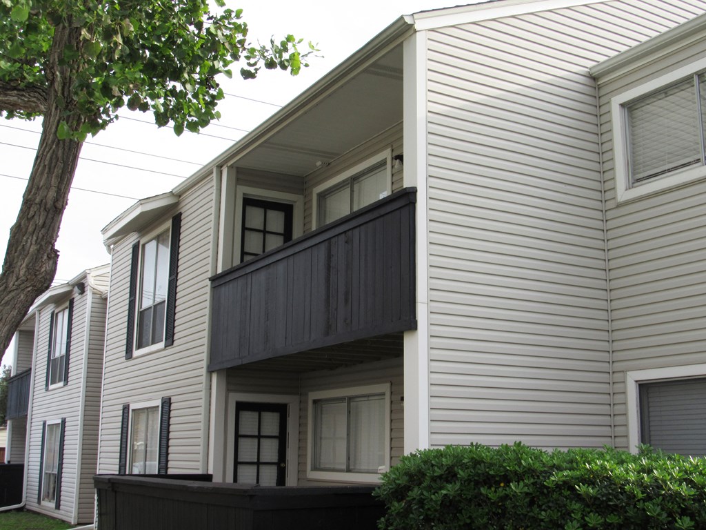 a white house with a balcony and a tree