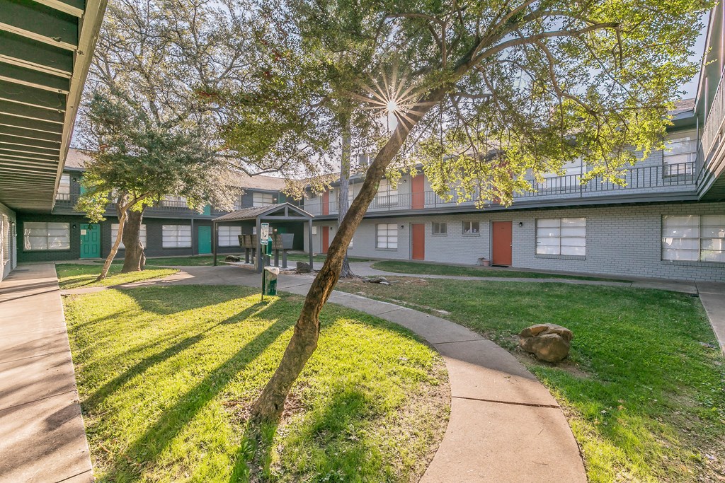 Courtyard walkway with green canopy at Chapel Creek Apartments in Corpus Christi.