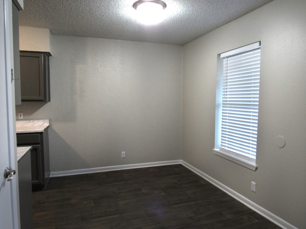 an empty room with a window and a kitchen