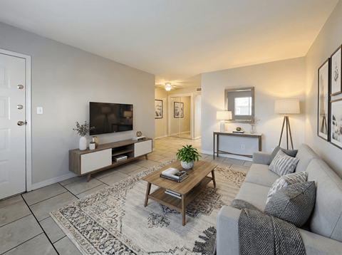 A living room with a grey couch, a wooden coffee table, and a television.