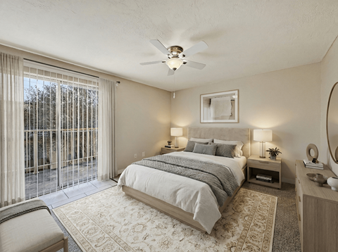 A bedroom with a large bed, a chair, and a ceiling fan.