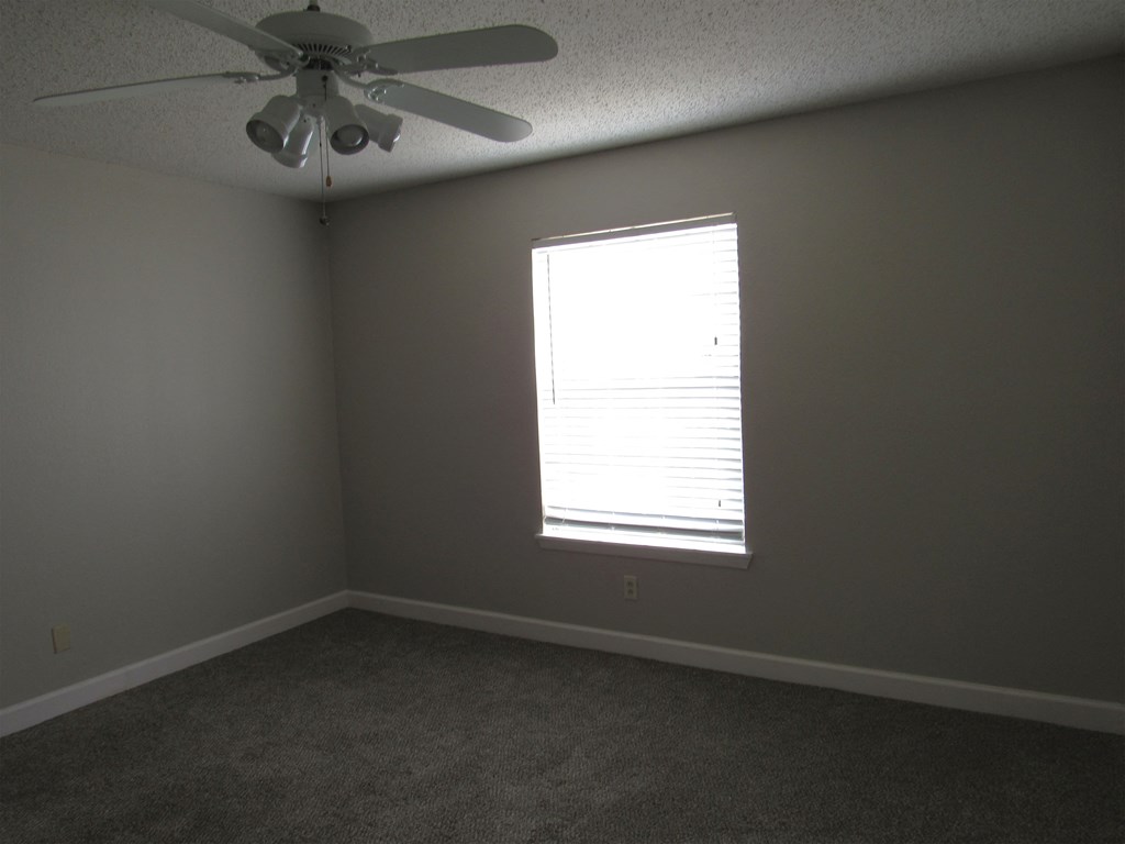 an empty room with a ceiling fan and a window