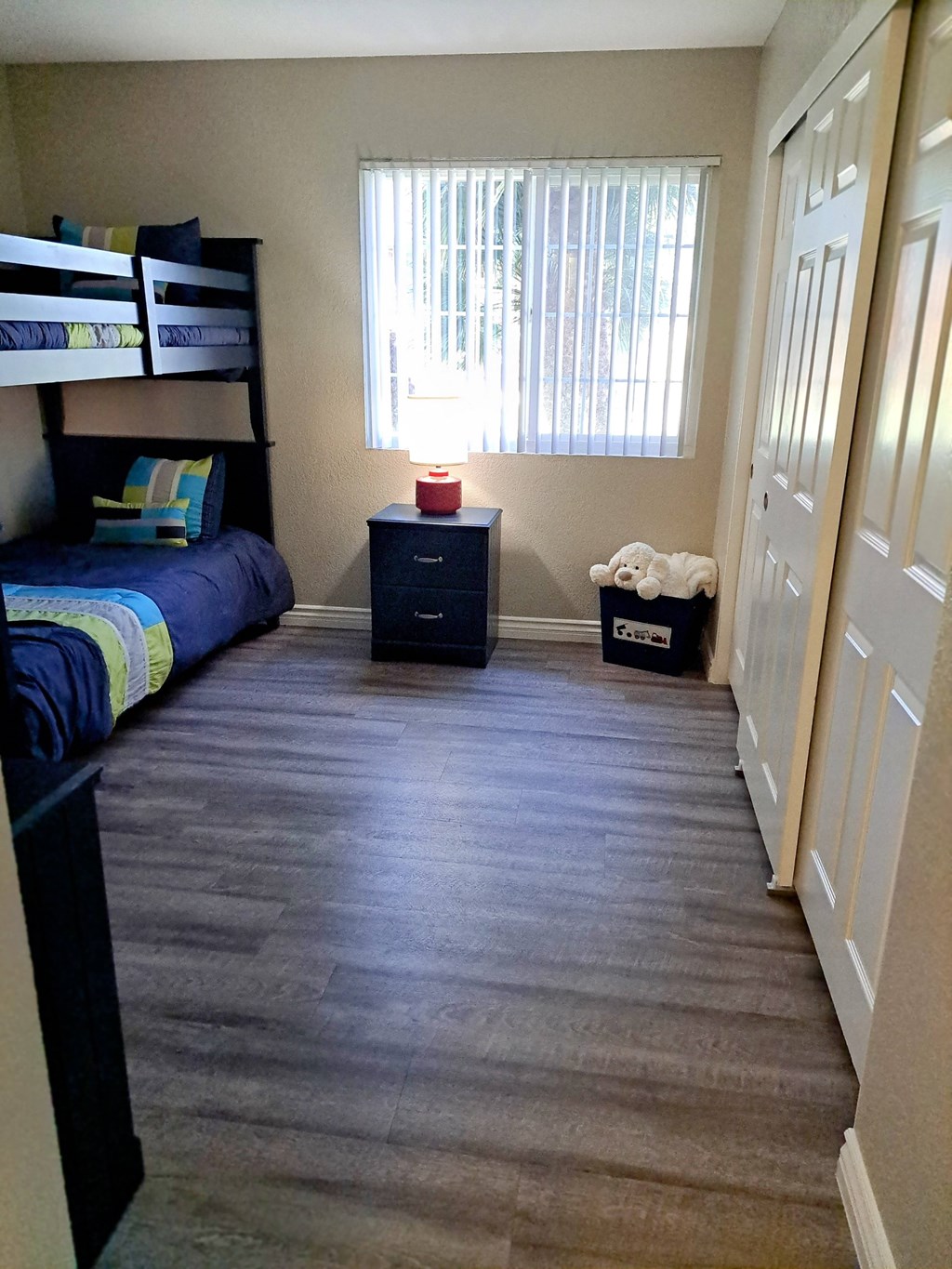 A room with a bunk bed, a nightstand, and a dresser at Raintree Apartments, CA 92346