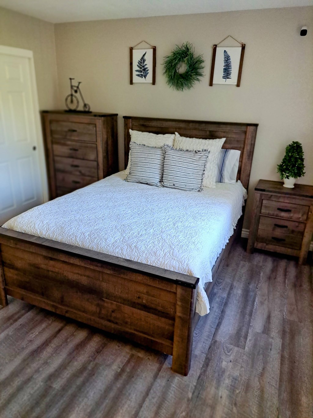 A bedroom with a large bed and a small tree on the nightstand at Raintree Apartments, CA 92346