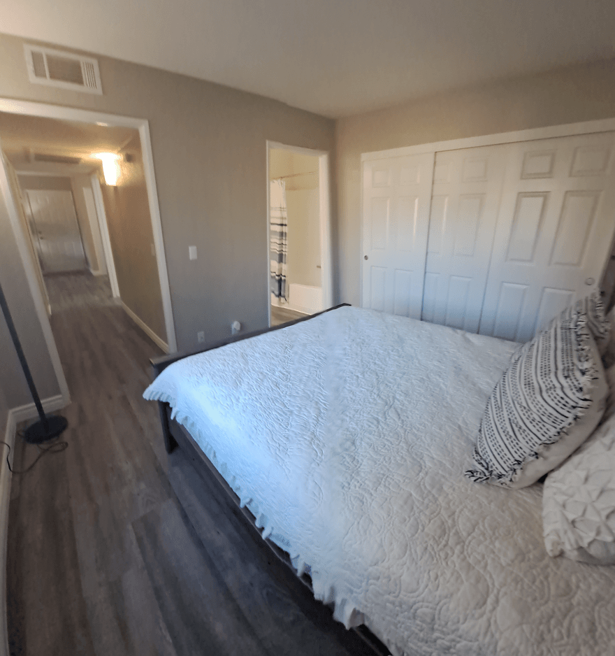 A bedroom with a bed, pillows, and a wooden floor at Raintree Apartments, CA 92346