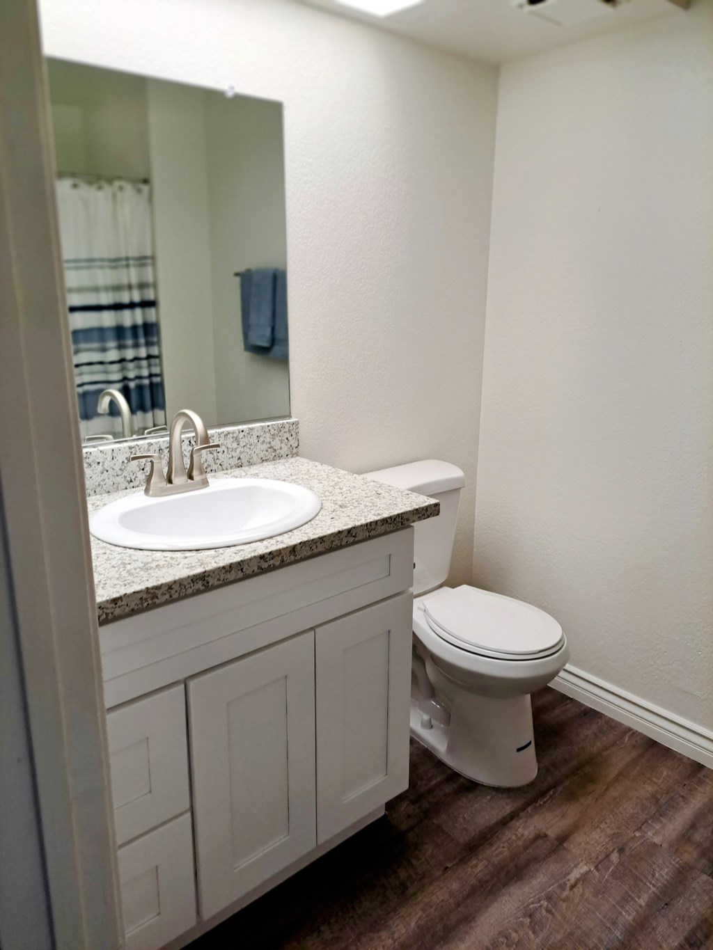 A white toilet sits next to a sink in a bathroom at Raintree Apartments, CA 92346