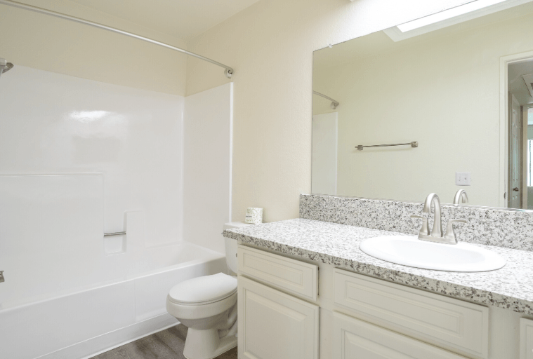 A white bathroom with a sink, toilet and bathtub at Raintree Apartments, CA 92346