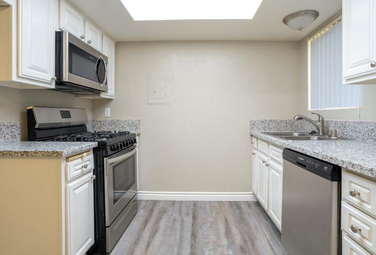 A kitchen with a black microwave above a black stove at Raintree Apartments, CA 92346