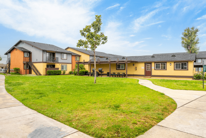 A row of houses with a green lawn in front at Raintree Apartments, CA 92346