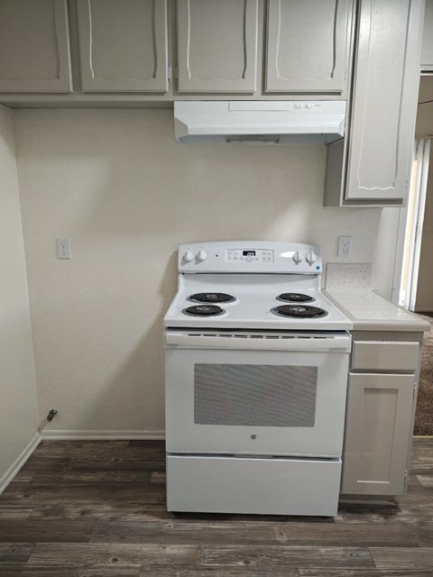 A white stove in a kitchen with wooden floors.