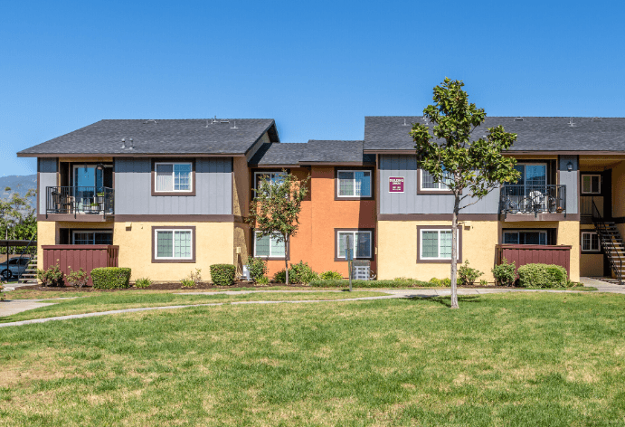 A tree stands in front of apartment buildings at Raintree Apartments, CA 92346