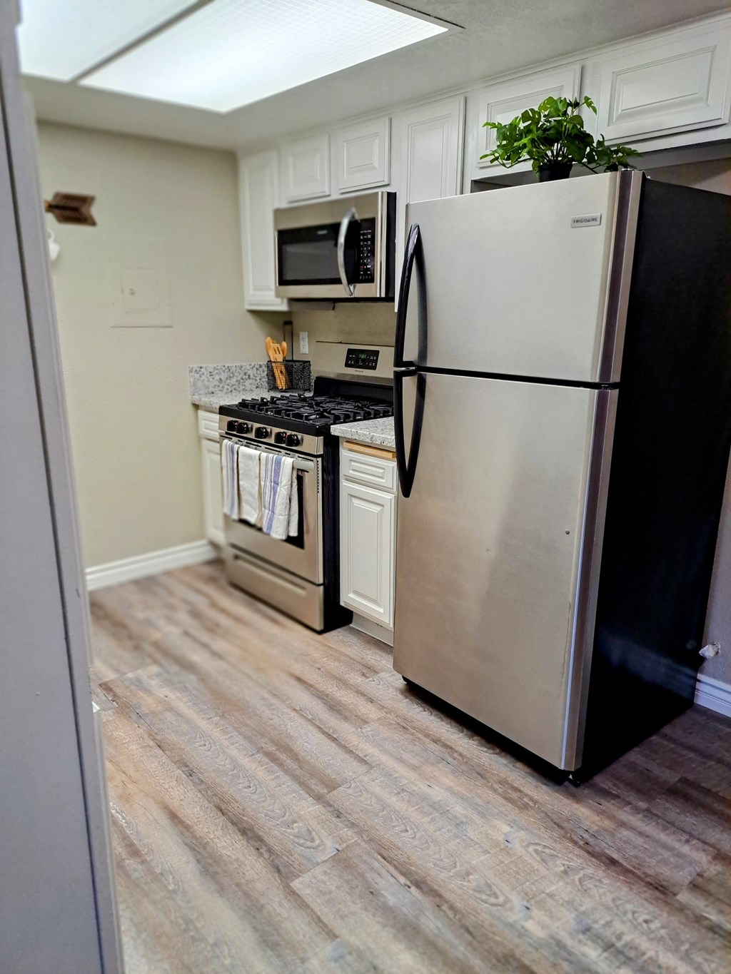 A black refrigerator stands in a kitchen with a stove and microwave in the background at Raintree Apartments, CA 92346