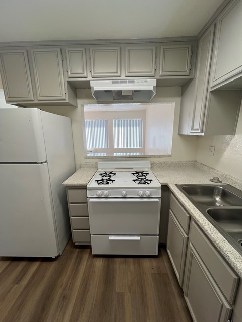 A kitchen with a white refrigerator, a white stove, and a white oven.