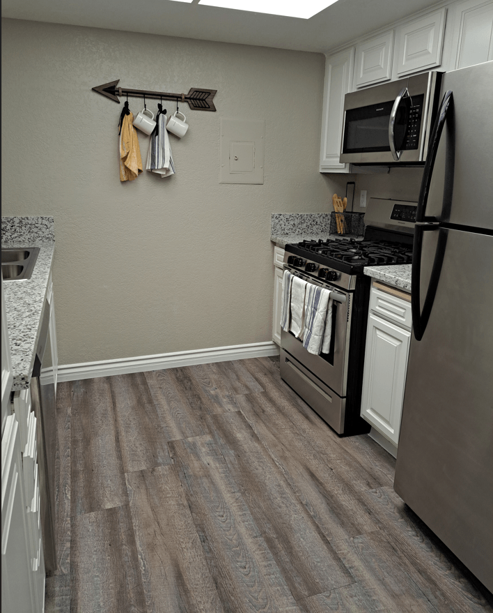 A kitchen with a black stove top oven and a black refrigerator at Raintree Apartments, CA 92346