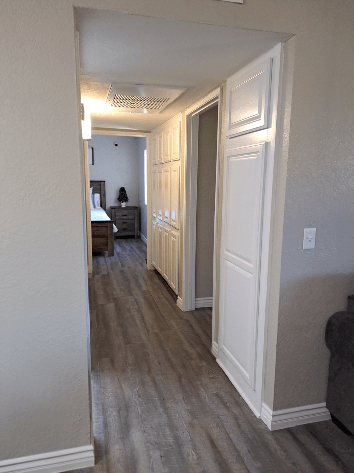 A hallway with a bedroom at the end at Raintree Apartments, CA 92346