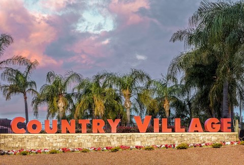 a sign for the county village with palm trees