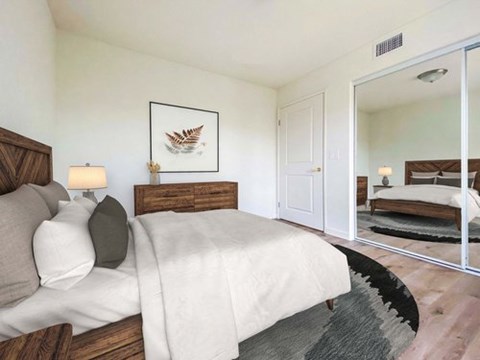 A bedroom with a large bed and a mirror on the wall.