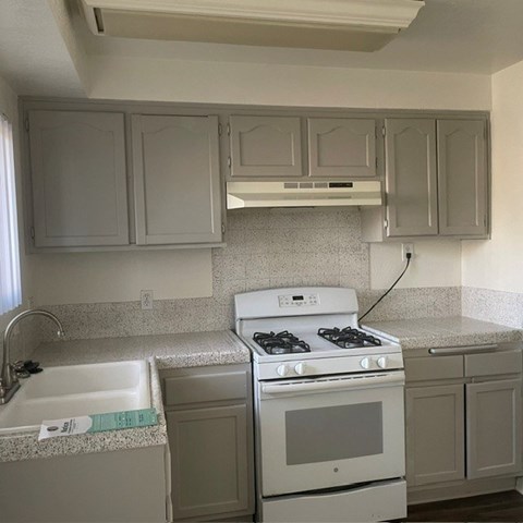 A kitchen with a white stove and cabinets.