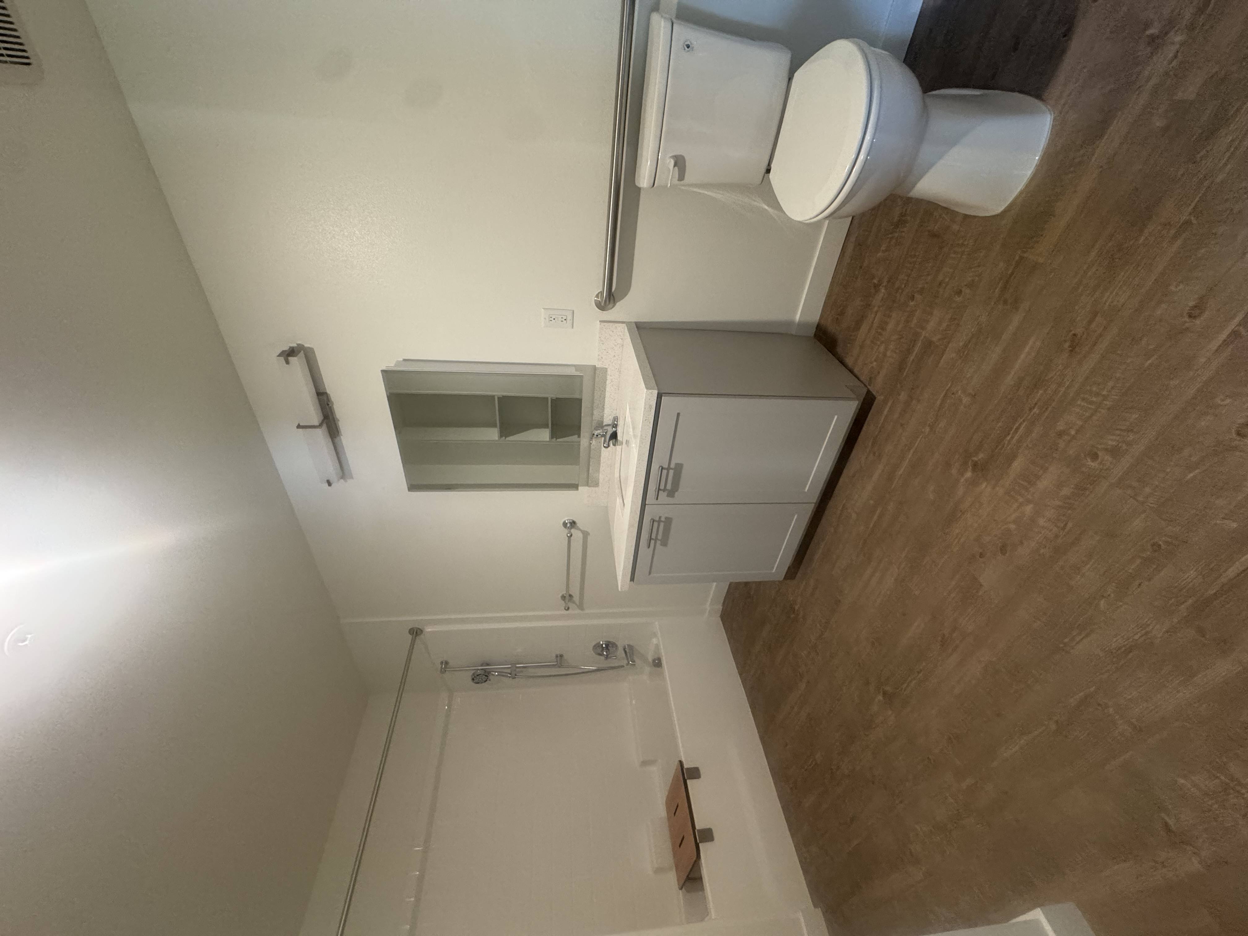 A white toilet is installed in a small bathroom with a brown floor.