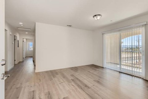 A spacious room with wooden flooring and white walls.