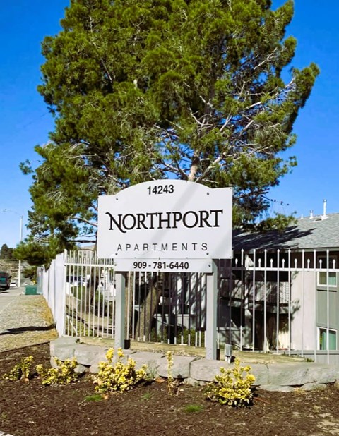 A sign for Northport Apartments is displayed in front of a tree.
