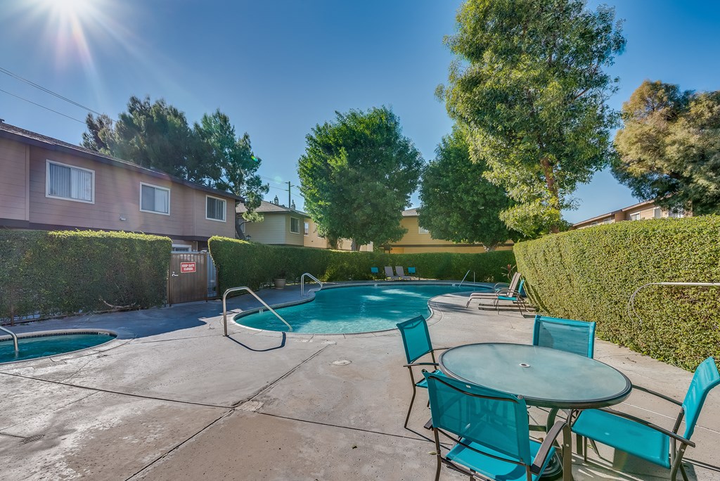 a pool with a hot tub and a table and chairs
